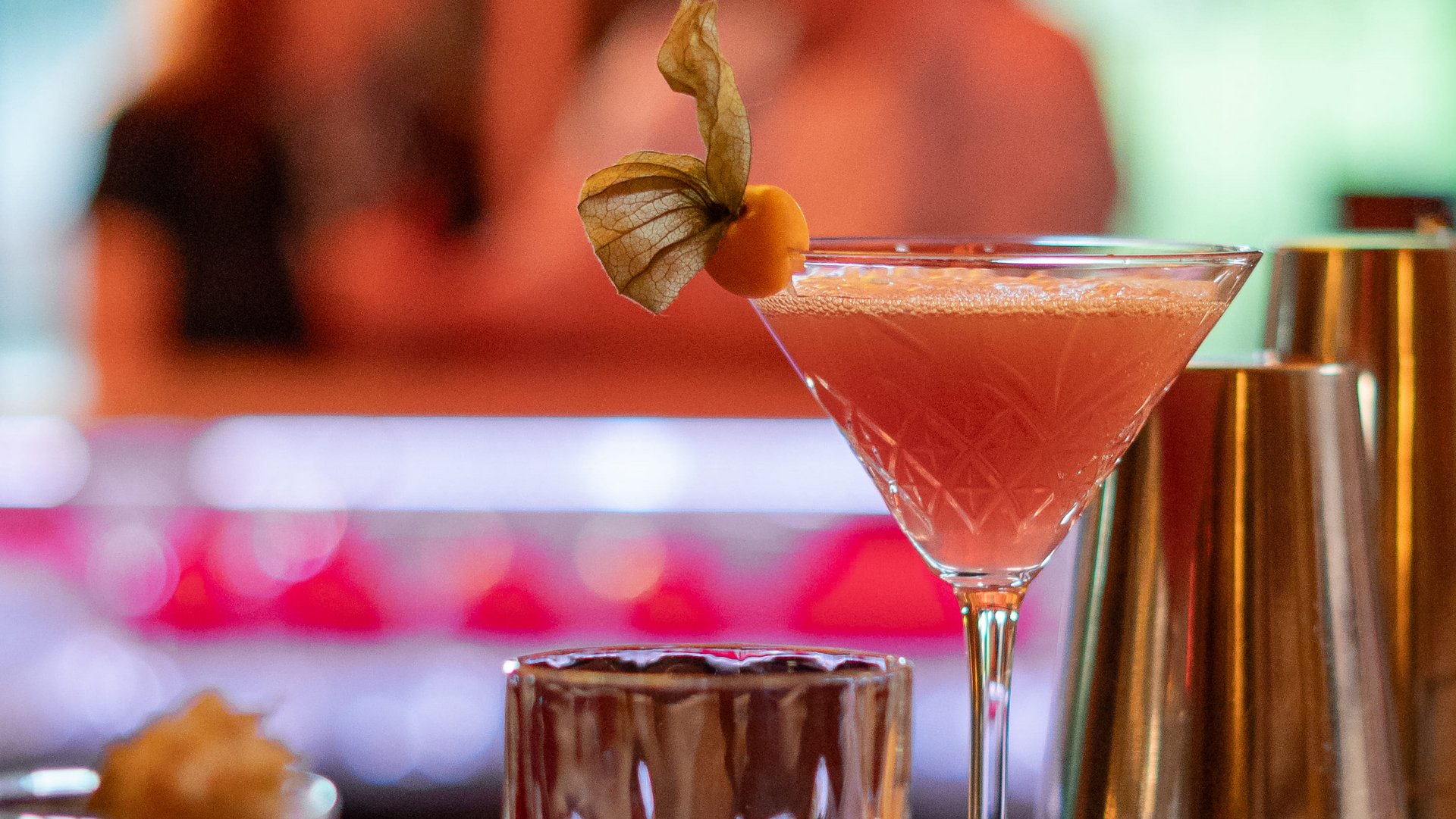 Ein eleganter pinkfarbener Cocktail serviert auf dem Holztresen der hoteleigenen Bar.