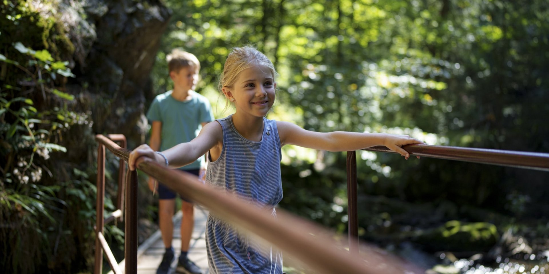 Kinder balancieren mutig über einen schmalen Holzsteg bei einem Ausflug im Schwarzwald.