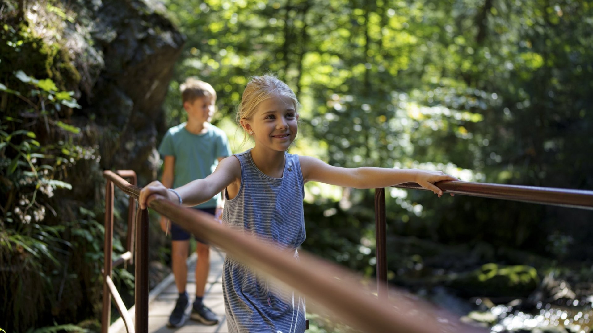 Kinder balancieren mutig über einen schmalen Holzsteg bei einem Ausflug im Schwarzwald.