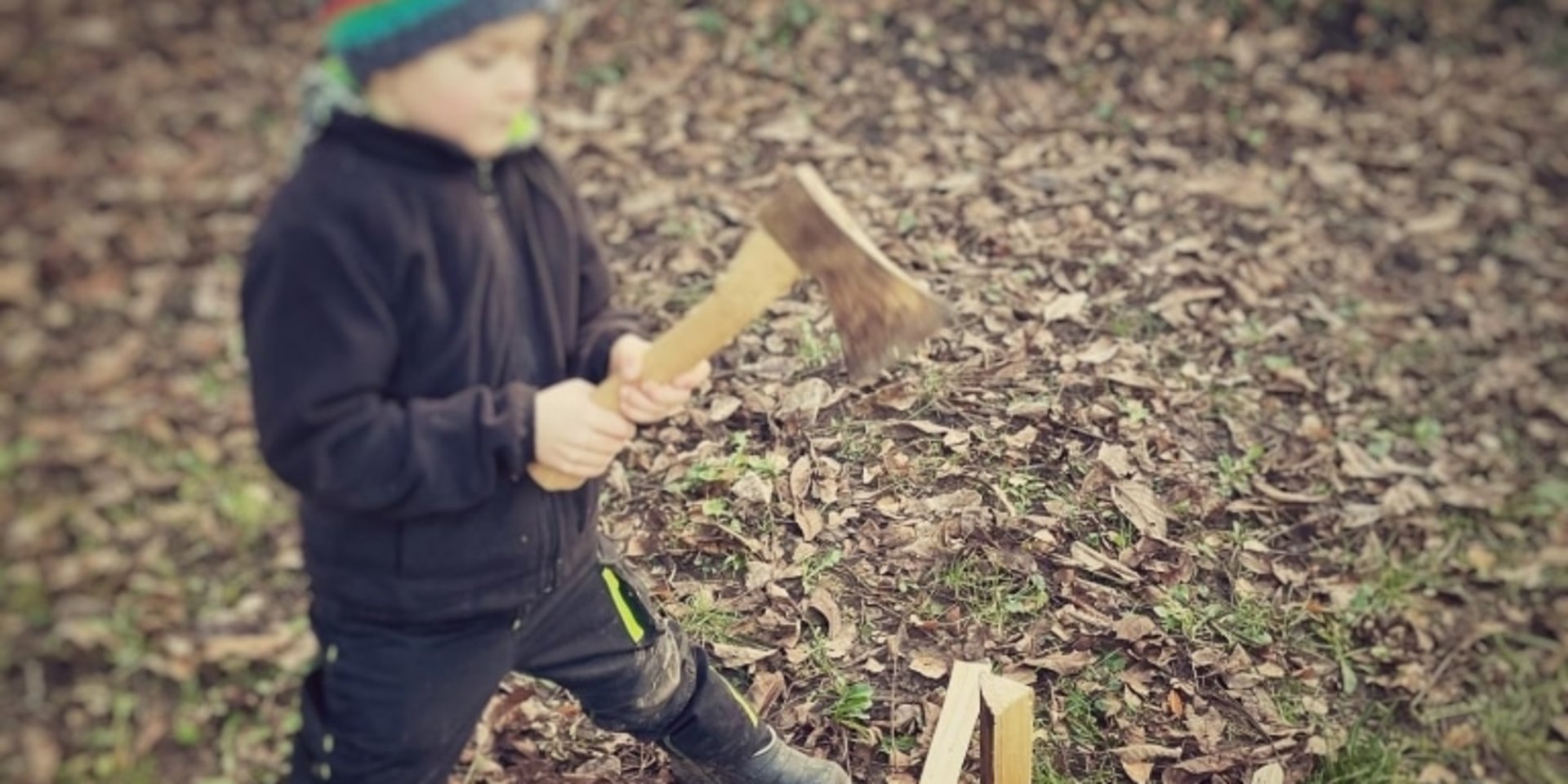 Ein Kind schnitzt konzentriert an einem Holzstock während eines Natur-Erlebnistages am Schluchsee.