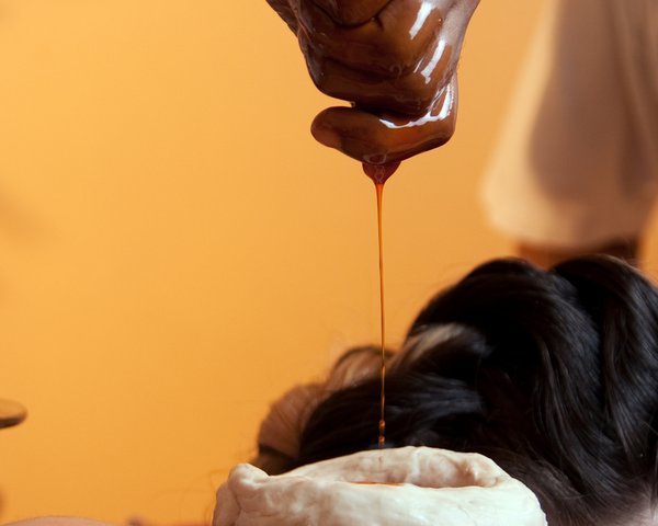 eine Hand lässt eine Flüssigkeit in eine Schale fließen die auf einem Rücken steht