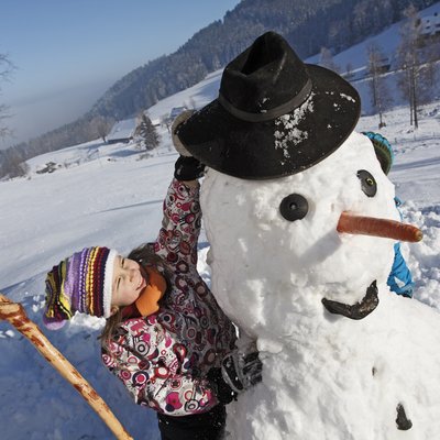 Kind beim Aufsetzen eines Hutes des Schneemanns