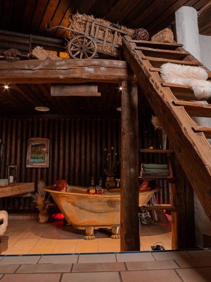Rustikaler Wellnessbereich im Stil einer historischen Badestube mit Holztreppe und Kupferwanne im Hotel Vier Jahreszeiten am Schluchsee.