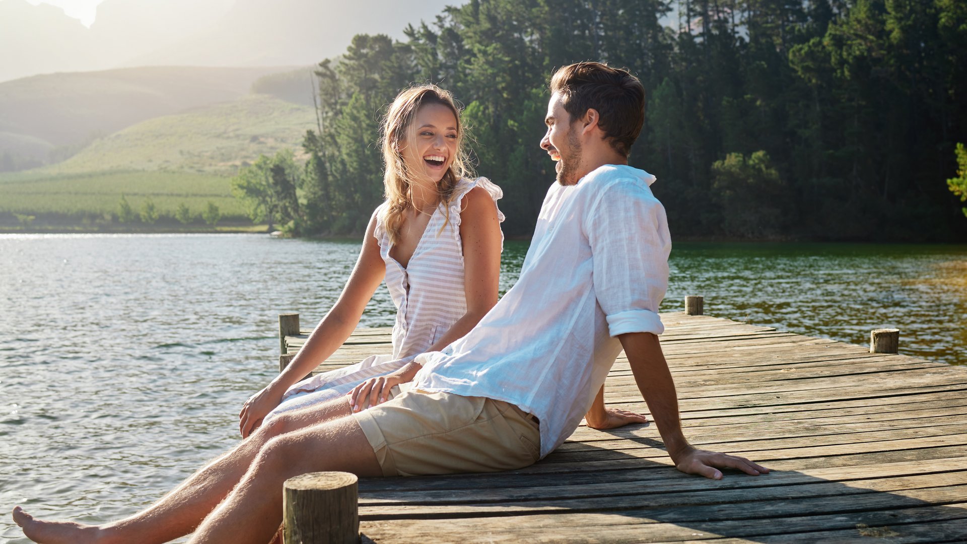Junges Paar sitzt im Sommer auf einem Steg am See