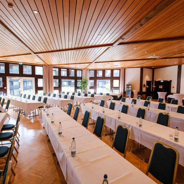 Blick durch den weitläufigen Veranstaltungssaal Riesenbühl mit eingedeckten Tischen für Seminare im Hotel Vier Jahreszeiten.