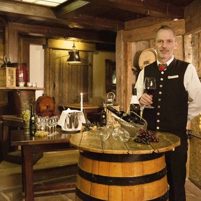 Blick in die urige, historische Weinstube des Hotels Vier Jahreszeiten mit einem Mitarbeiter in traditioneller Kleidung