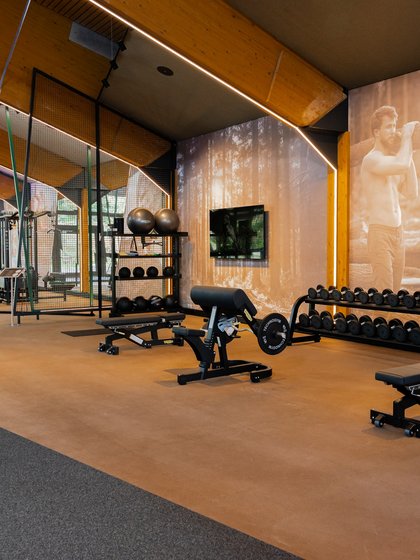Großzügiger Hantelbereich und Trainingsbänke unter der markanten Holzdecke der hoteleigenen Sporthalle.