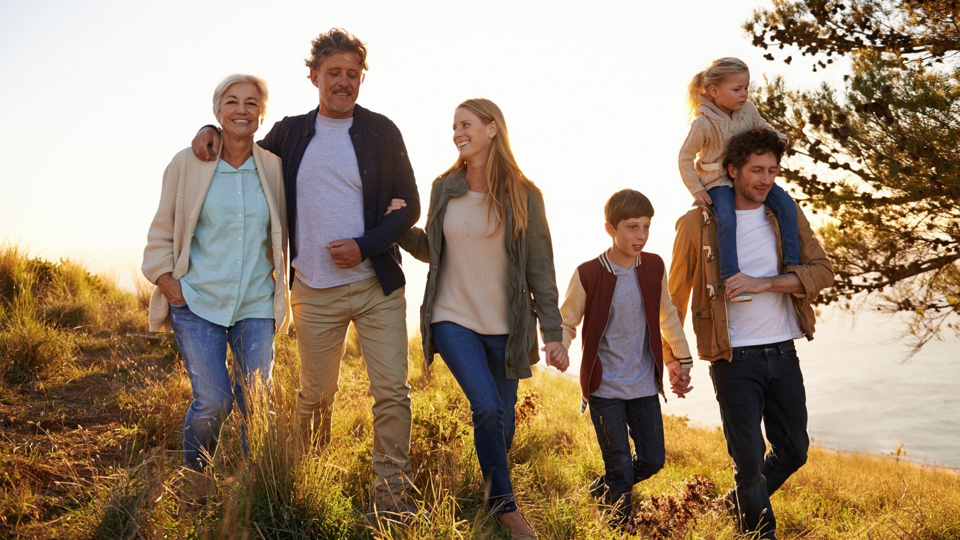 Eine Familie wandert gemeinsam bei Sonnenuntergang über eine Anhöhe im Schwarzwald.