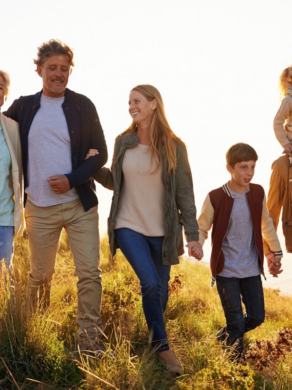 Eine Familie wandert gemeinsam bei Sonnenuntergang über eine Anhöhe im Schwarzwald.