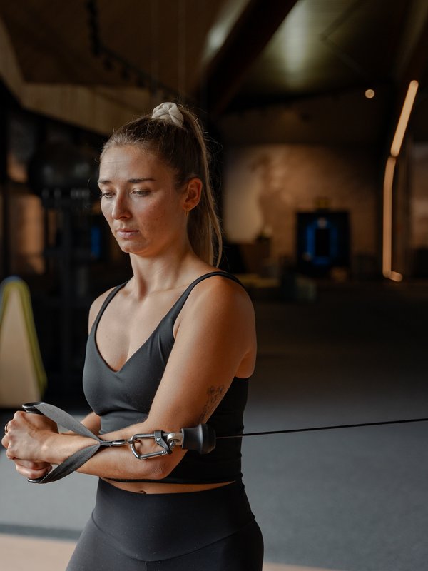 Eine Trainerin unterstützt einen Gast bei Übungen im modernen Fitnessbereich des Hotels Vier Jahreszeiten am Schluchsee.