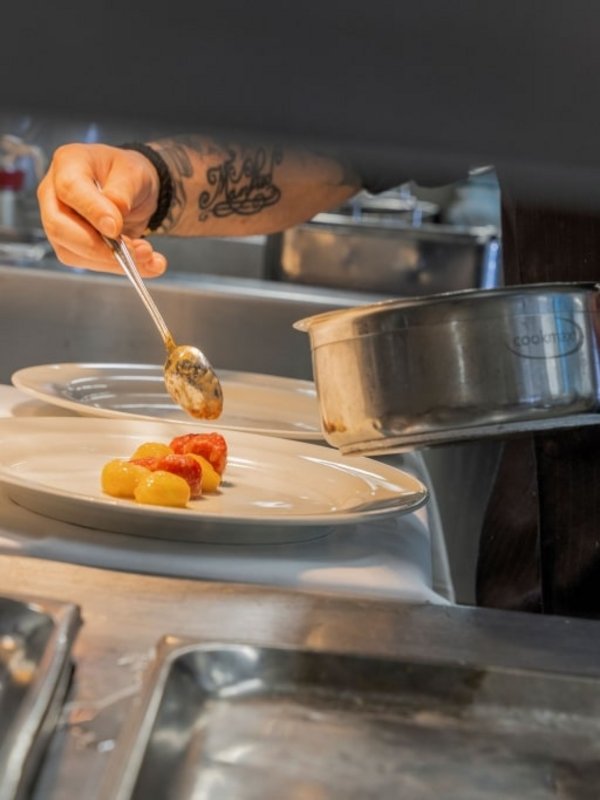 Ein Koch richtet mit höchster Präzision Speisen in der professionellen Hotelküche am Schluchsee an.