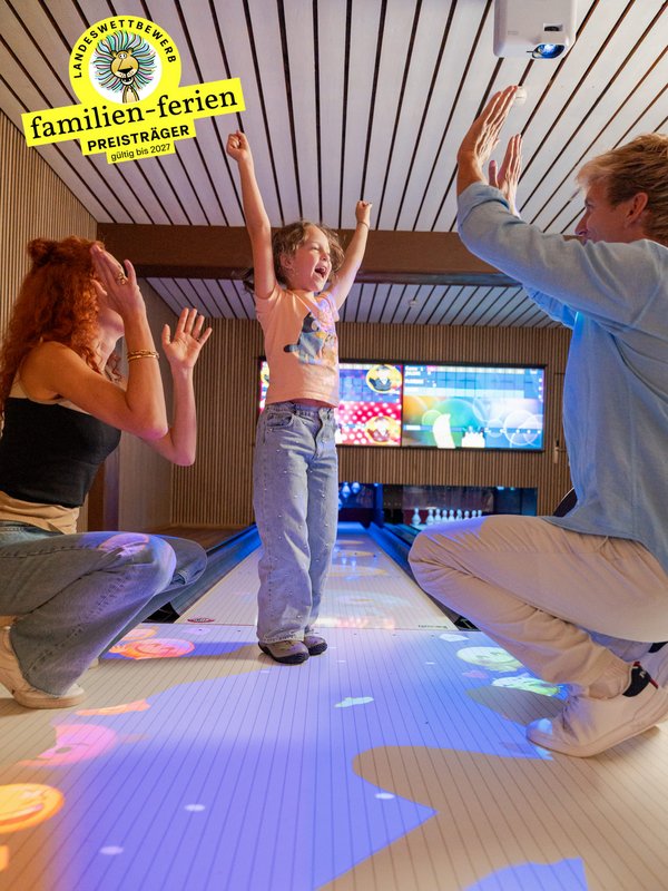 Kinder tanzen ausgelassen auf einer interaktiven, leuchtenden Spielfläche im Hotel Vier Jahreszeiten.