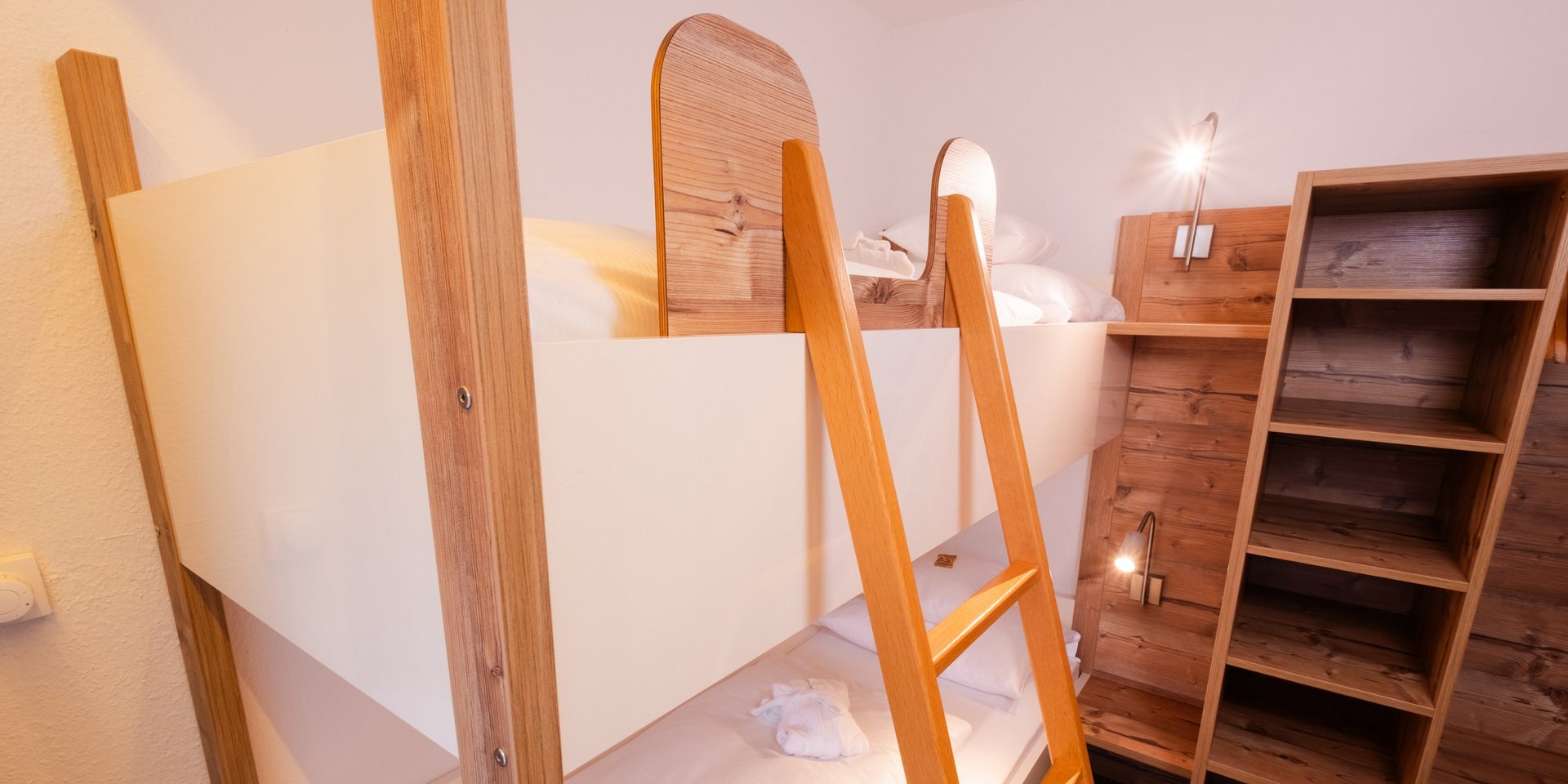 Kinderbereich mit hellem Etagenbett aus Holz und praktischen Regalen im Familienzimmer Wald.