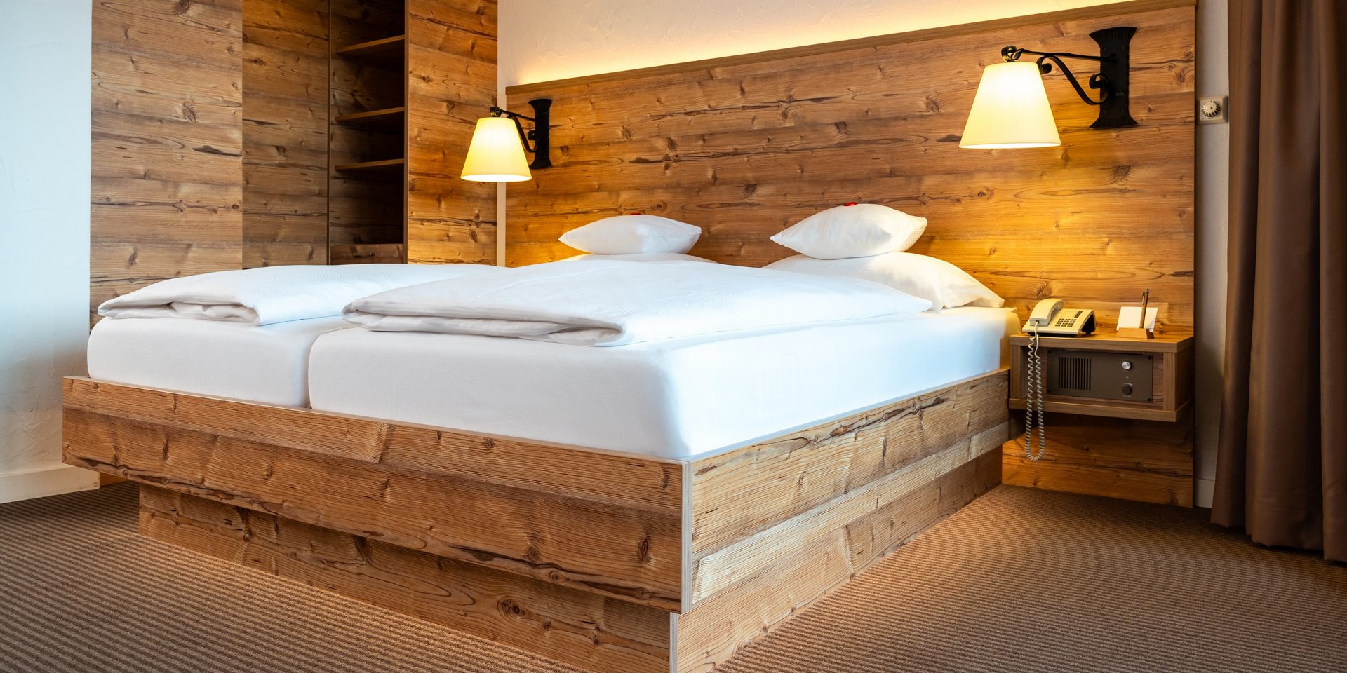 Rustikales Doppelbett mit indirekter Beleuchtung im Hotel Vier Jahreszeiten am Schluchsee.