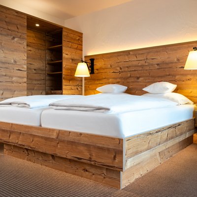 Rustikales Doppelbett mit indirekter Beleuchtung im Hotel Vier Jahreszeiten am Schluchsee.