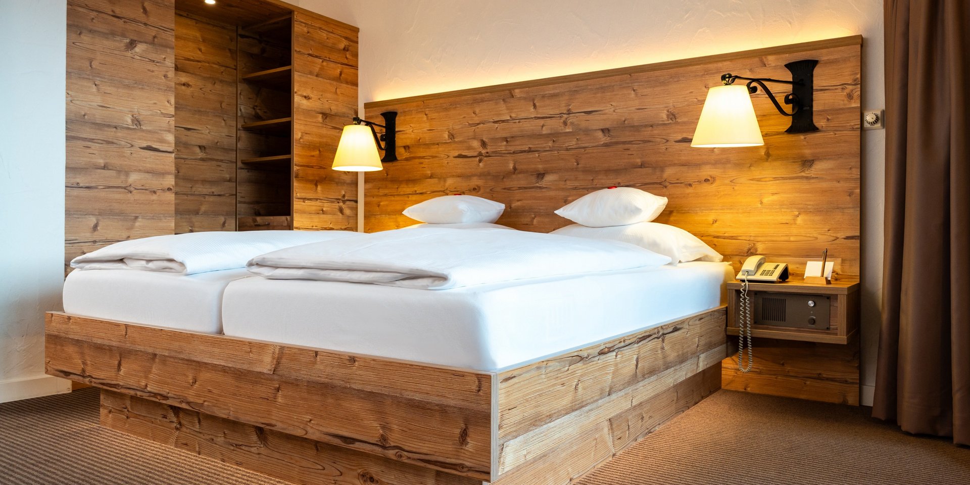 Rustikales Doppelbett mit indirekter Beleuchtung im Hotel Vier Jahreszeiten am Schluchsee.