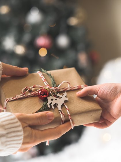 Zwei Hände beim Überreichen eines Weihnachtsgeschenks