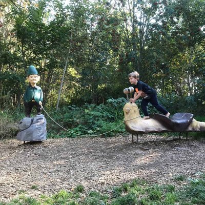 Kinder spielen auf geschnitzten Holzfiguren im Wald nahe dem Hotel Vier Jahreszeiten am Schluchsee.