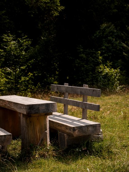 Wanderpause im Schwarzwald: Rustikale Holzbank mit Tisch im kühlen Schatten.