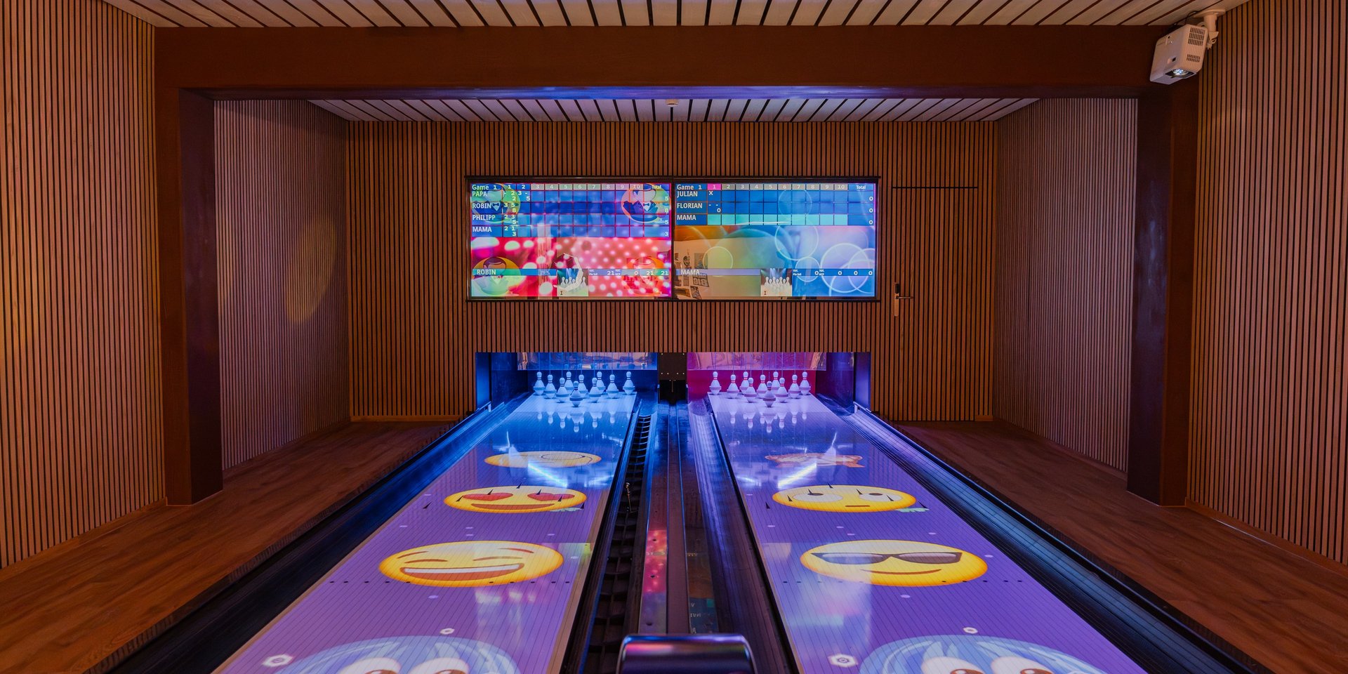 Blick auf die modernen, lila leuchtenden Bowlingbahnen für Kinder und Familien im Hotel Vier Jahreszeiten.