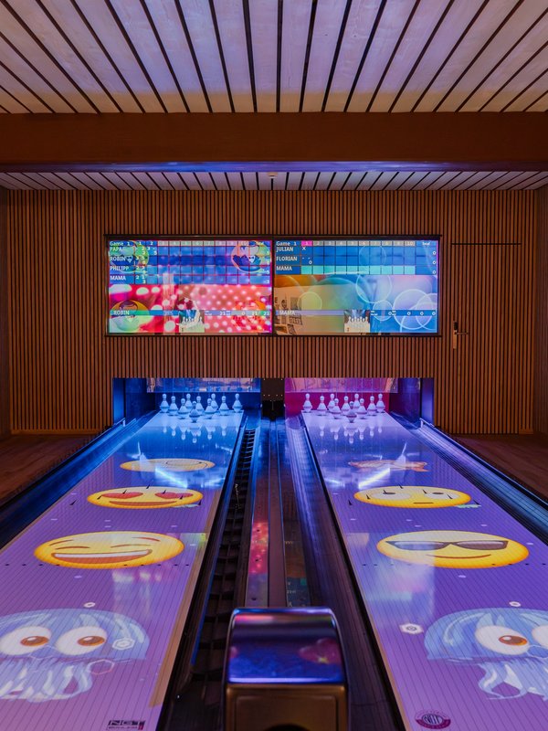 Blick auf die modernen, lila leuchtenden Bowlingbahnen für Kinder und Familien im Hotel Vier Jahreszeiten.