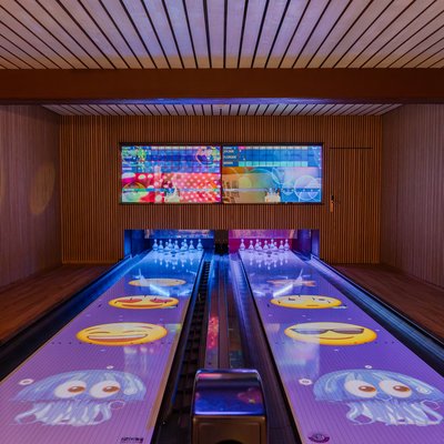 Blick auf die modernen, lila leuchtenden Bowlingbahnen für Kinder und Familien im Hotel Vier Jahreszeiten.