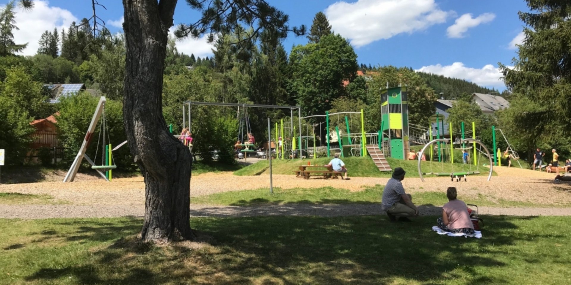 Ein schattiger Waldspielplatz mit Klettergerüsten unter hohen Bäumen im Schwarzwald.