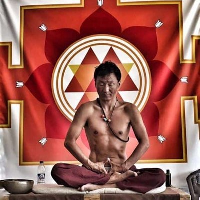 Chumba Lama während einer rituellen Zeremonie vor einem roten Wandteppich.