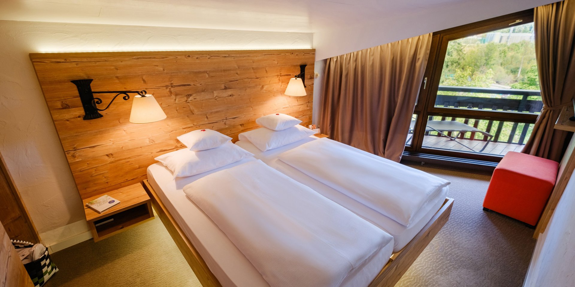 Helles Schlafzimmer der Klassik Suite Wald mit großem Doppelbett und Balkonzugang im Hotel Vier Jahreszeiten am Schluchsee.