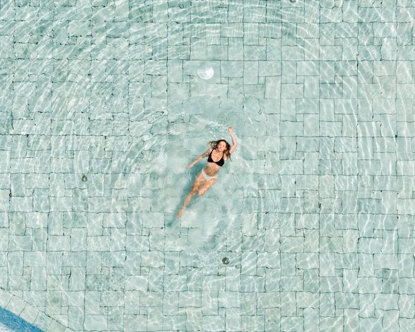 Frau schwimmt in Rückenlage im Außenpool