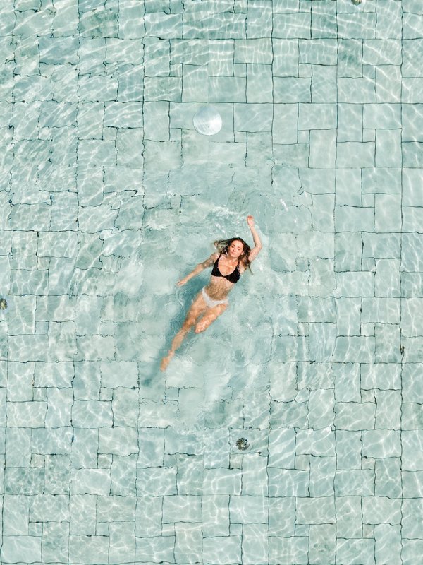 Frau schwimmt in Rückenlage im Außenpool