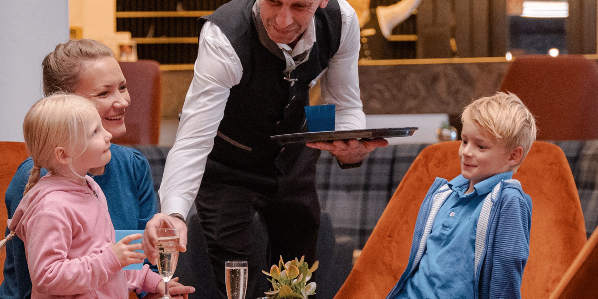 Ein Servicemitarbeiter im Hotel Vier Jahreszeiten am Schluchsee bedient freundlich eine Familie im Restaurant.