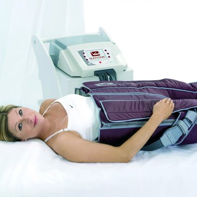 Eine Frau entspannt während einer apparativen Lymphdrainage-Behandlung (Slimyonik) im Wellnessbereich des Hotels Vier Jahreszeiten.