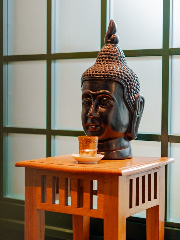 Ein Buddha-Kopf aus dunklem Stein auf einem kleinen Holzaltar vor einem Fenster im Hotel Vier Jahreszeiten am Schluchsee.