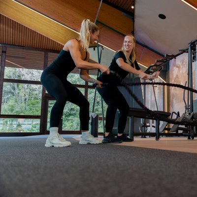 Zwei Frauen beim gemeinsamen Lauftraining auf den Laufbändern der Sporthalle.