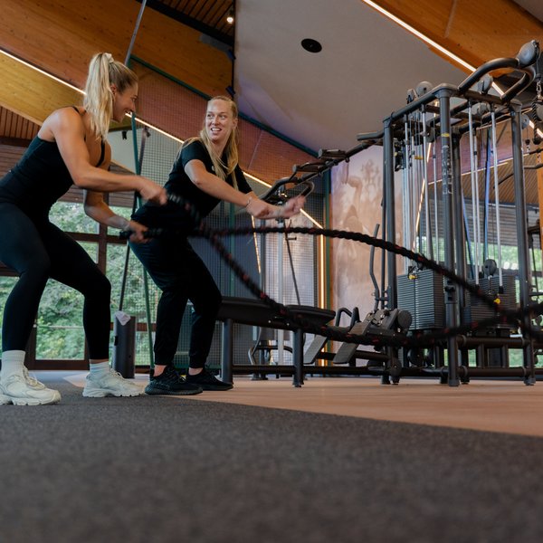 Zwei Frauen beim gemeinsamen Lauftraining auf den Laufbändern der Sporthalle.