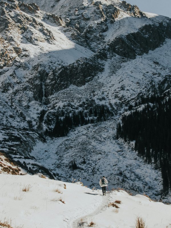 Beeindruckende Aussicht von einem Wanderpfad auf verschneite Gipfel im Winter.