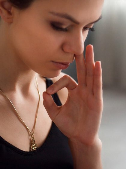 Eine junge Frau praktiziert eine meditative Atemübung (Pranayama) in einem ruhigen Raum.