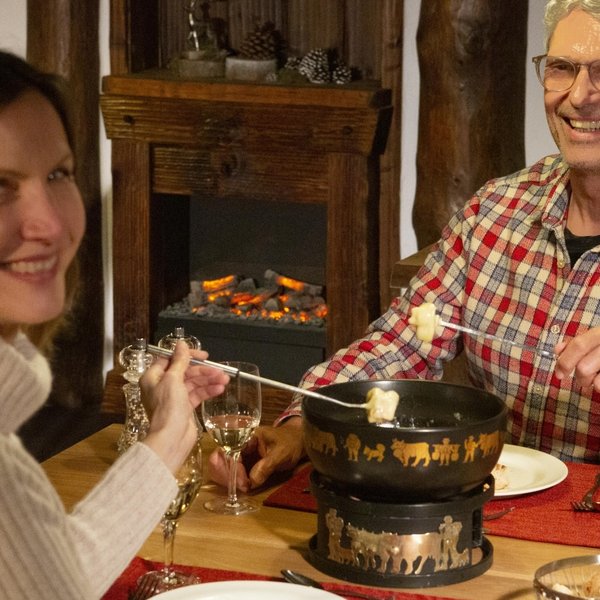 Ein Paar genießt ein traditionelles Fondue im gemütlich-rustikalen Schwiitzer Stuebli.
