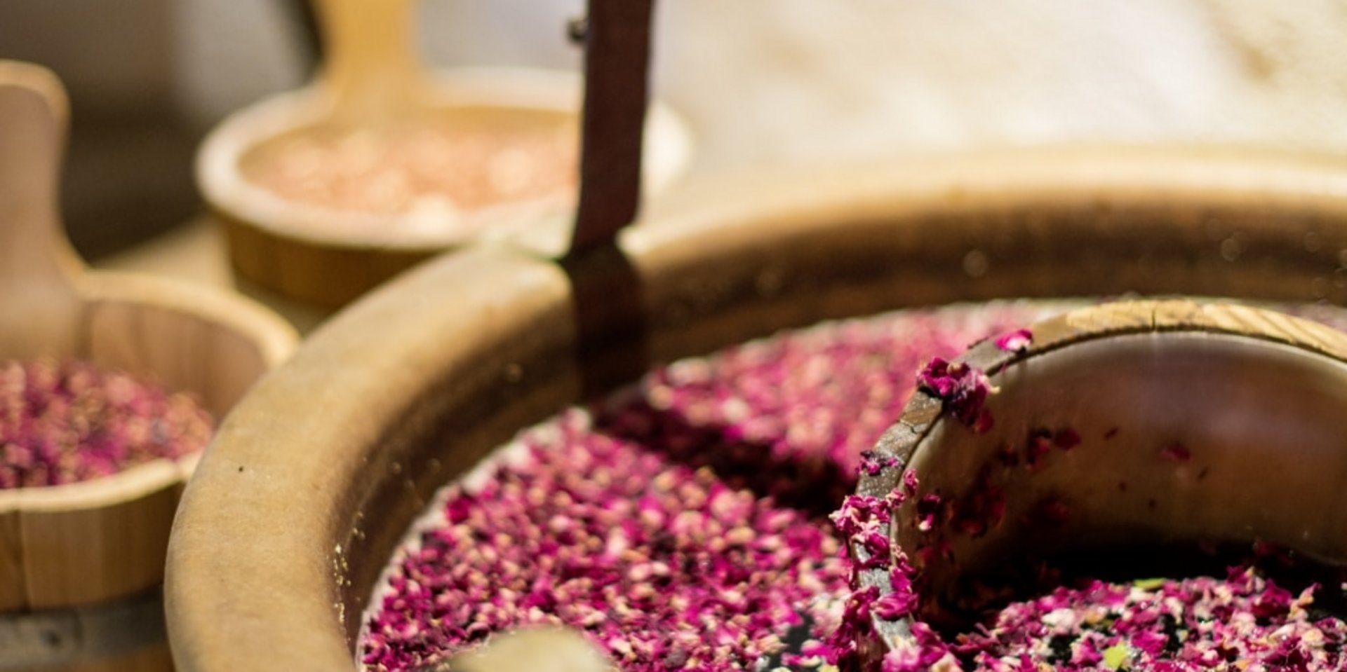 Rustikale Holzzuber gefüllt mit duftenden lila Blütenblättern für ein entspannendes Aroma-Bad im Hotel Vier Jahreszeiten am Schluchsee.