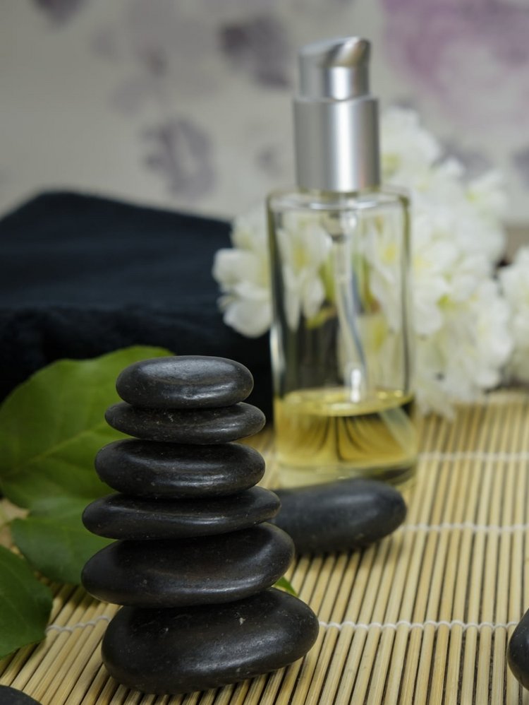 Stillleben mit aufgetürmten schwarzen Massagesteinen, einer Teekanne und einer brennenden Kerze im Hotel Vier Jahreszeiten am Schluchsee.