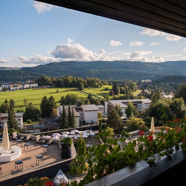 Panoramablick von einem Hotelbalkon über die Poolanlage in die weite Natur.
