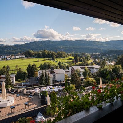 Panoramablick von einem Hotelbalkon über die Poolanlage in die weite Natur.