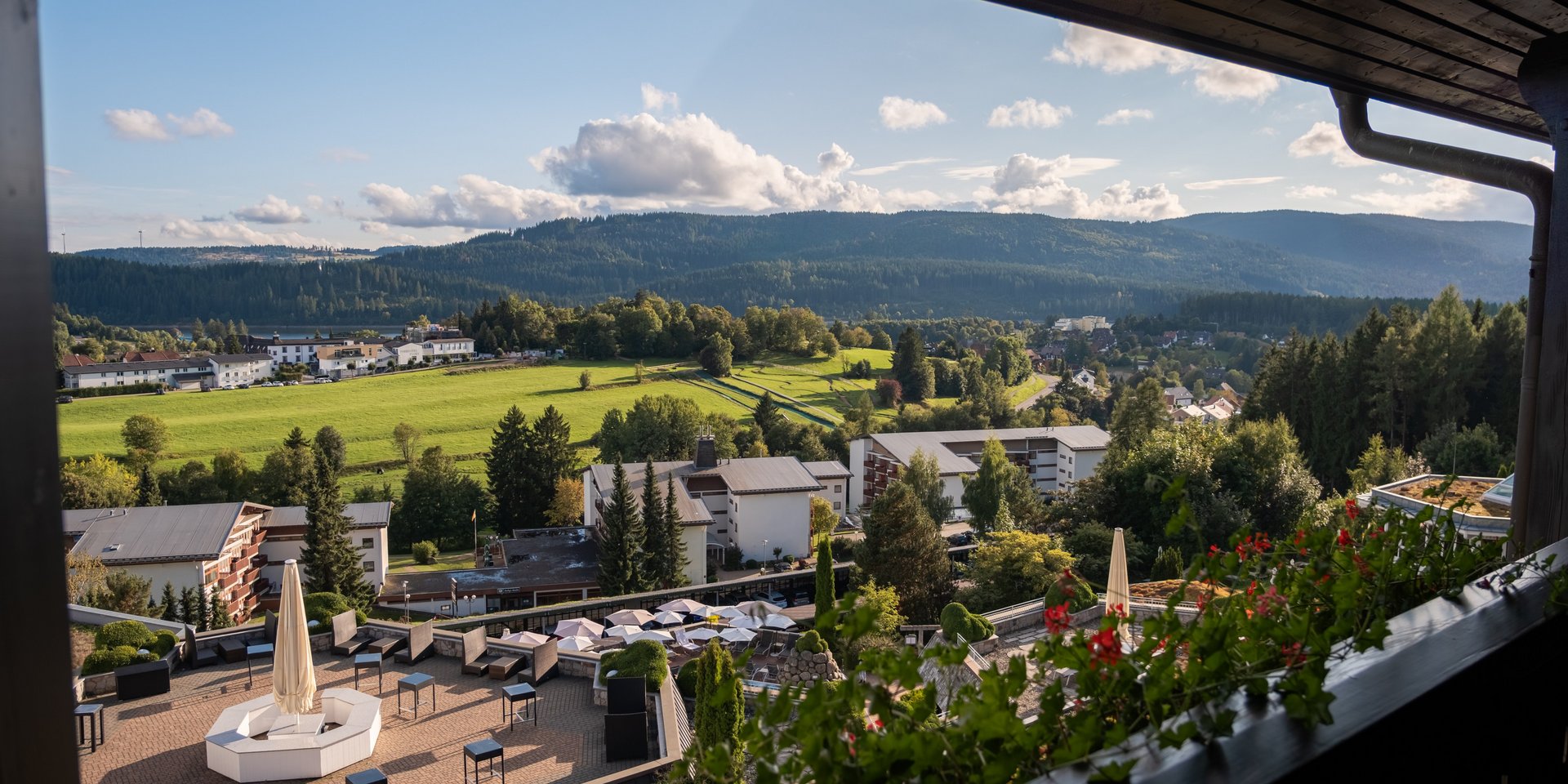 Panoramablick von einem Hotelbalkon über die Poolanlage in die weite Natur.