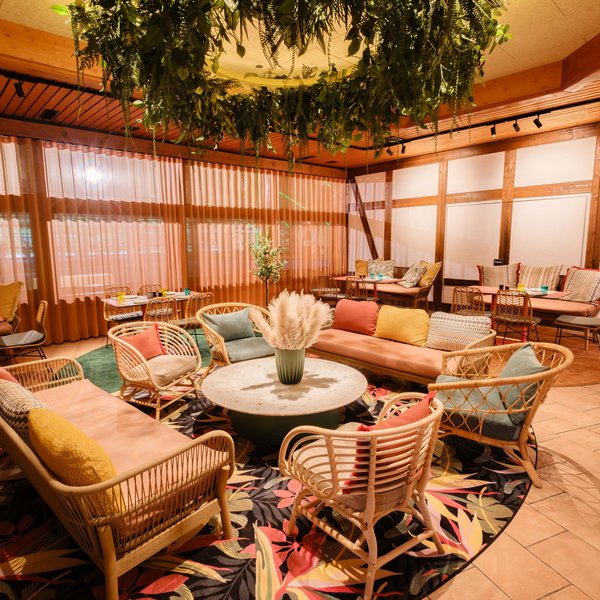 Farbenfroher Loungebereich im Restaurant Lucia mit gemütlichen Korbsesseln und modernem Design.
