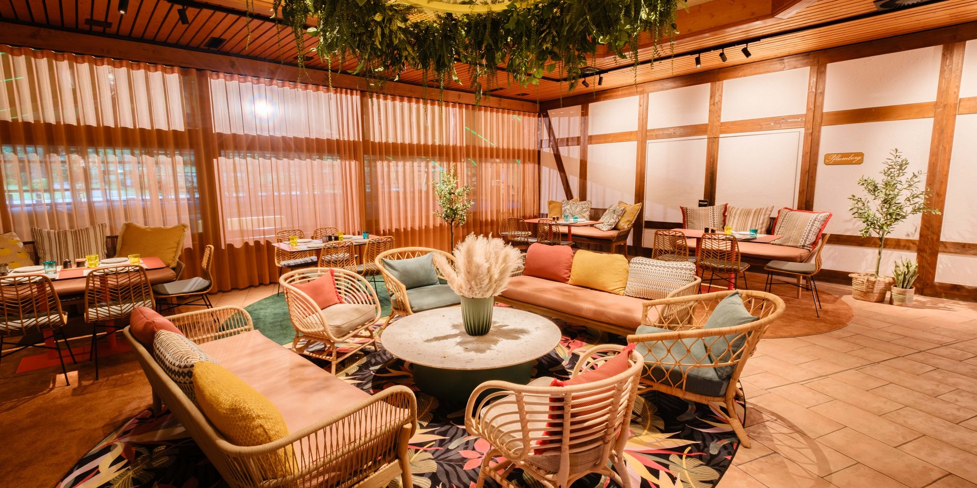 Farbenfroher Loungebereich im Restaurant Lucia mit gemütlichen Korbsesseln und modernem Design.