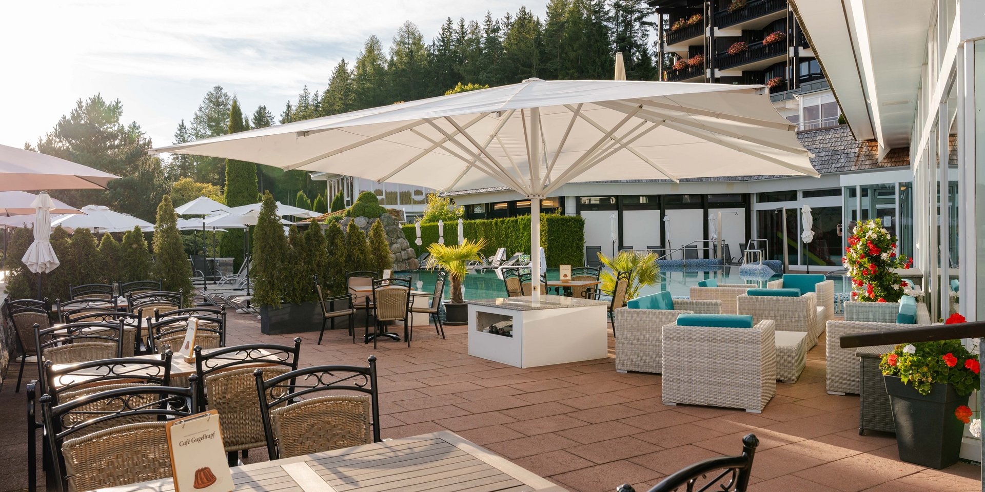 Sonnige Außenterrasse des Cafés Gugelhupf im Hotel Vier Jahreszeiten am Schluchsee mit gemütlichen Sitzgruppen.
