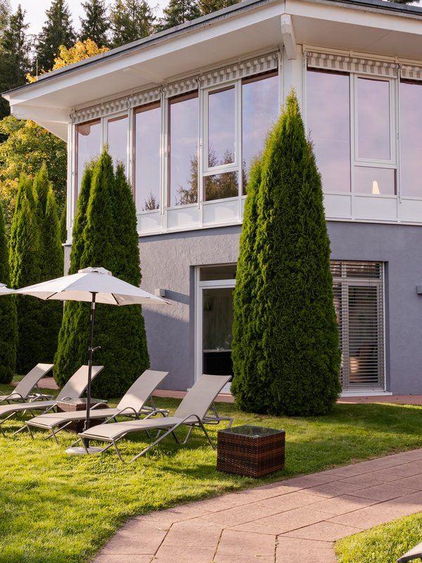 Gepflegte Liegewiese mit Sonnenliegen vor der hellen Hotelfassade.