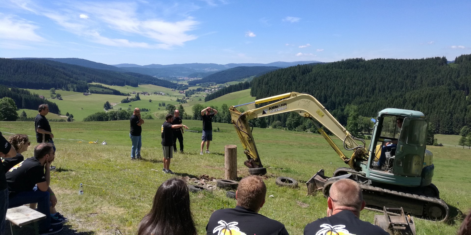 Viele Leute sitzen um einen Bagger und schauen was dieser macht - Schwarzwaldgaudi