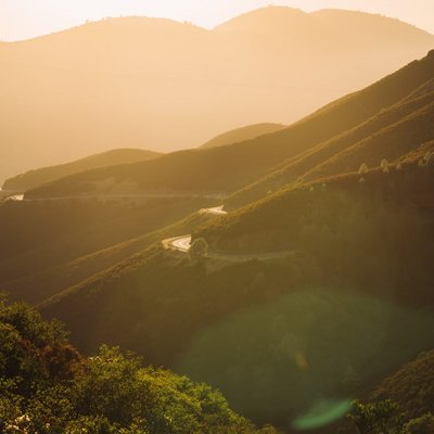 Die goldene Abendsonne bricht durch die Wipfel bewaldeter Schwarzwaldhügel.